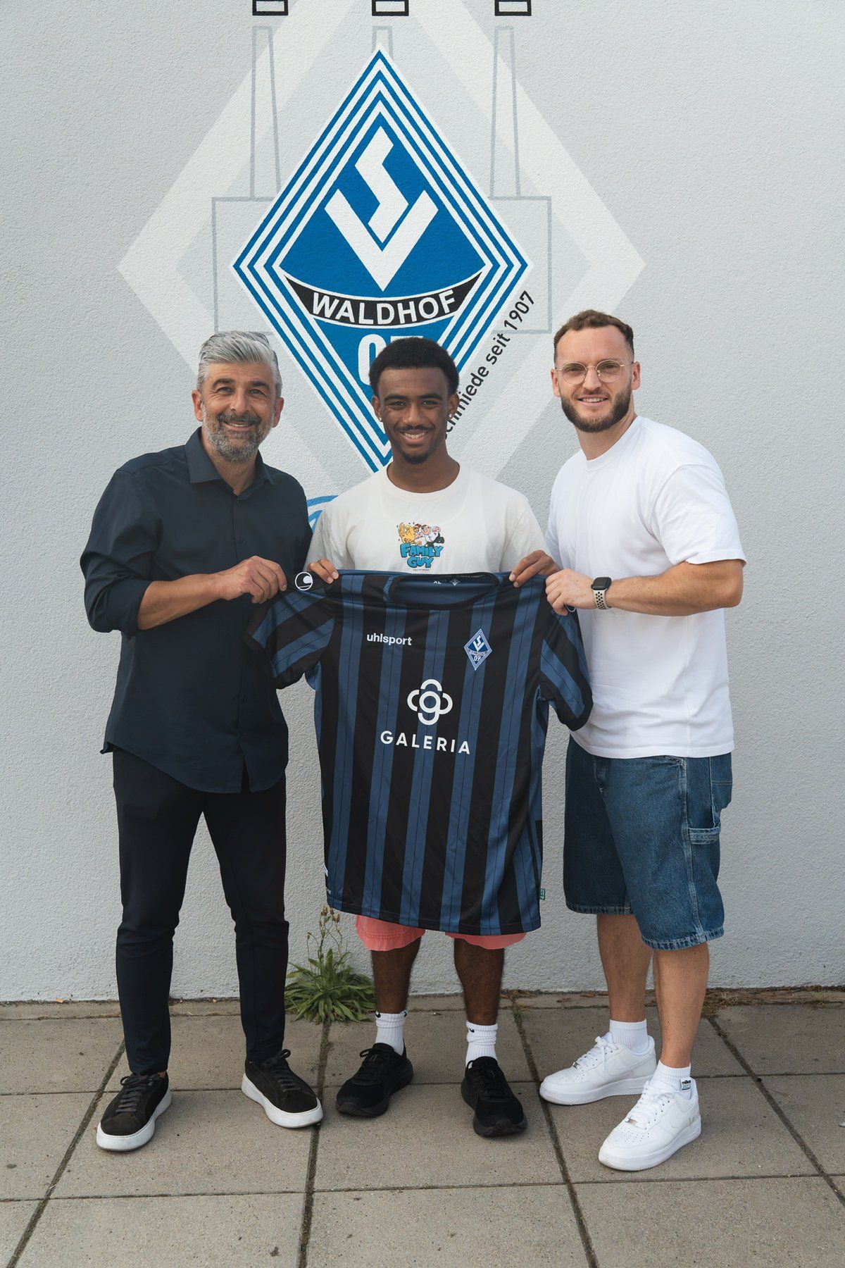 Sebastian Richardson holding his SV Waldhof Mannheim shirt, together with Leon Hammel and a club representative